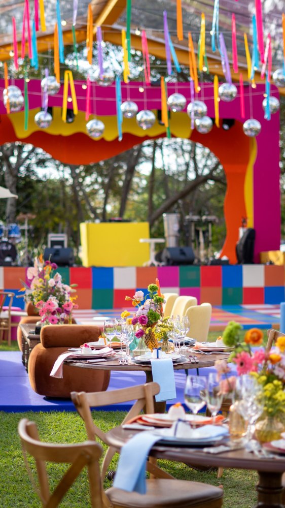 Décor festif coloré avec tables, fleurs et scène